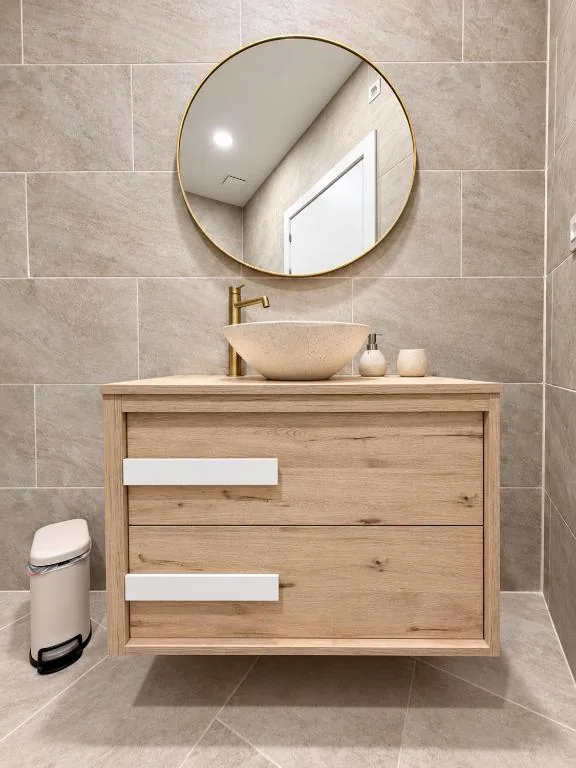 Lavabo sobre mueble de madera y espejo redondo del Estudio Don Pedro II Bajo