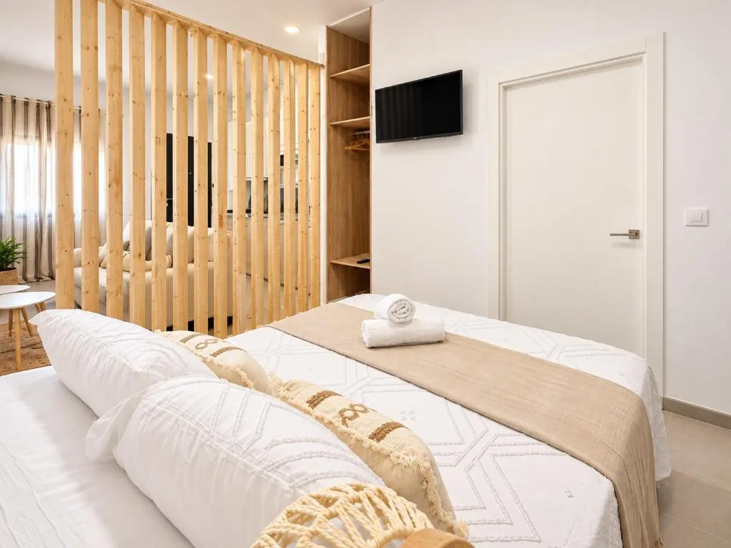 Dormitorio con cama doble junto a la separación de madera del Estudio Don Pedro II Bajo